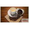 A cup of coffee on a table with beans
